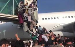 Aereo in fase di decollo inseguito sulla pista da una folla di uomini